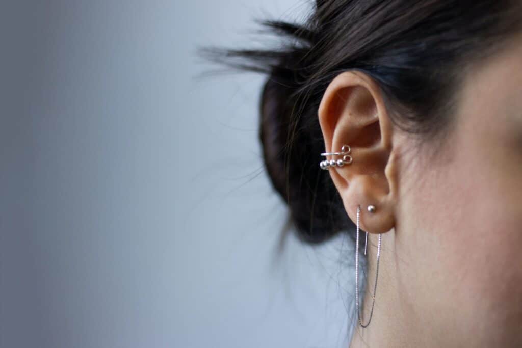 woman's ear with black hair and silver earrings 