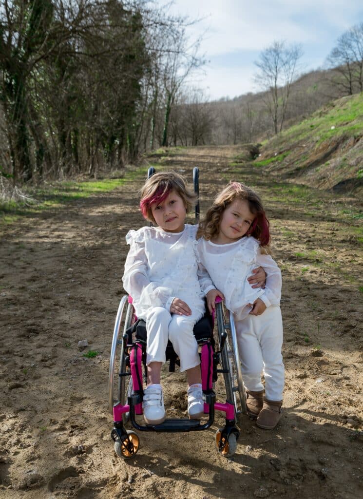 Sisters on dirt road in wheelchair